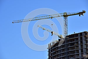 Tower crane lifting concrete bucket for pouring concrete during construction residential building on blue sky background. Builder