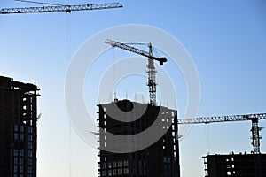 Tower crane lifting concrete bucket for pouring concrete during construction residential building on blue sky background. Builder