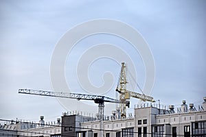 Tower crane near a house under construction in the city during the day