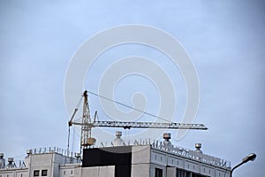 Tower crane near a house under construction in the city during the day