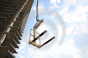 Tower crane near unfinished building against cloudy sky on construction site