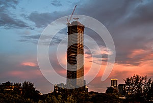 Tower crane on top of an unfinished building in the evening at Bangkok, Thailand