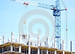 A tower crane works on a construction site. Builders carry out lifting work. The construction of a high-rise building