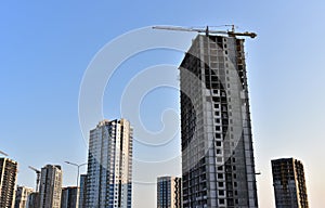 Tower cranes in action at construction site on blue sky background. A crane the conctruct the high-rise building. New residential