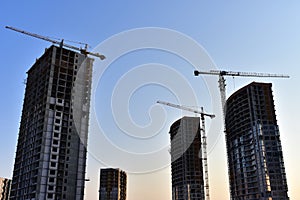 Tower cranes in action at construction site on blue sky background. A crane the conctruct the high-rise building. New residential