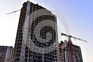 Tower cranes in action at construction site on blue sky background. A crane the conctruct the high-rise building. New residential