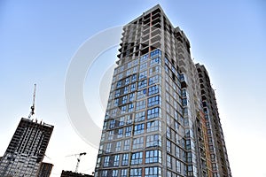 Tower cranes in action at construction site on blue sky background. A crane the conctruct the high-rise building. New residential