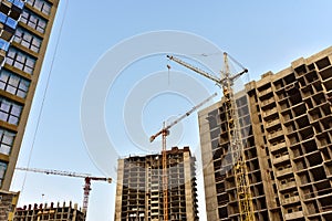 Tower cranes in action at construction site. Construction of skeleton of new modern residential buildings. Preparing to pour of