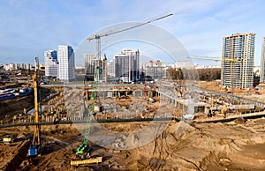 Tower cranes in action at construction site. Crane during formworks. Soil Compactor leveling ground for construct of foundation