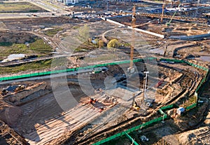 Tower cranes in action at construction site. Crane during formworks. Soil Compactor leveling ground for construct of foundation