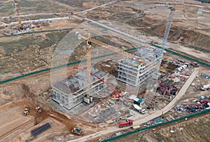 Tower cranes in action at construction site. Crane during formworks. Soil Compactor leveling ground for construct of foundation