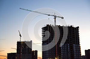 Tower cranes in action at construction site on sunset background. Crane the build the high-rise building. New residential