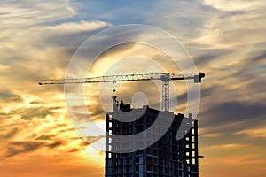 Tower cranes in action at construction site on sunset background. Crane the build the high-rise building. New residential