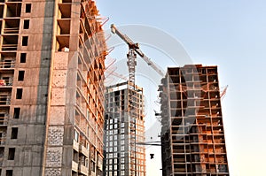 Tower cranes in action at construction site on sunset background. Crane the build the high-rise building. New residential