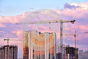 Tower cranes in action at construction site on sunset background. Crane the build the high-rise building. photo