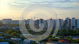 Tower cranes on buliding site in modern city against sunset