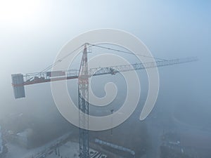 tower cranes on a construcion site with dense fog aerial view