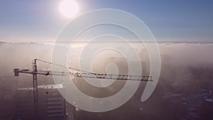 tower cranes on a construcion site with dense fog aerial view