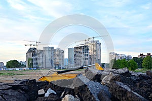 Tower cranes constructing a new building at a construction site on the sunset and blue sky background.