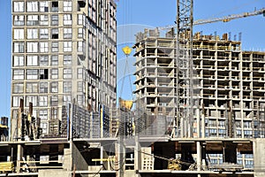 Tower cranes constructing a new residential build. Luffing jib tower crane and workers being poured concrete into formwork of