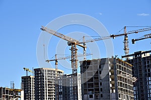 Tower cranes constructing a new residential build. Luffing jib tower crane and workers being poured concrete into formwork of