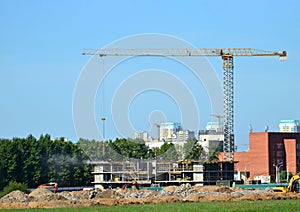 Tower cranes constructing a new residential building at a construction site against blue sky.