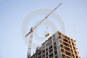 Tower cranes constructing a new residential building at a construction site against blue sky