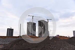 Tower cranes constructing a new residential building at a construction site against blue sky