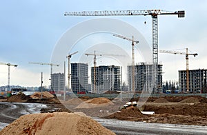 Tower cranes constructing a new residential building at a construction site against blue sky. Renovation program, development,