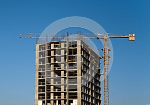 Tower cranes constructing a new residential building at a construction site against blue sky. Renovation program, development,