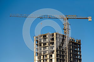 Tower cranes constructing a new residential building at a construction site against blue sky. Renovation program, development,