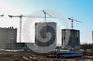 Tower cranes constructing a new residential building at a construction site against blue sky. Renovation program, development,