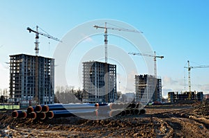 Tower cranes constructing a new residential building at a construction site against blue sky. Renovation program, development,