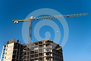 Tower cranes constructing a new residential building at a construction site against blue sky. Renovation program, development,