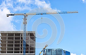 Tower cranes erect high-rise skyscrapers against the blue sky. Copy space