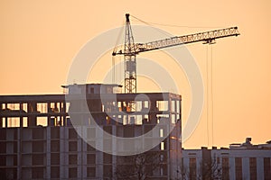 Tower cranes at high residential apartment buildings construction site in evening. Real estate development