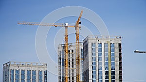 Tower cranes next to modern high-rise buildings under construction