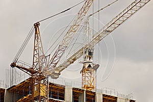 Tower cranes work during the construction of a multi-story building. New apartments for residents and premises for offices. Risky