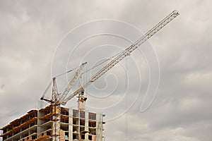 Tower cranes work during the construction of a multi-story building. New apartments for residents and premises for offices. Risky