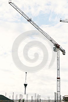Tower cranes work at the construction site of a multi-storey building against the background of a blue sky with white
