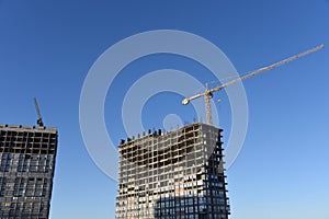 Tower cranes working at construction site against blue sky background. Crane build the high-rise building. New residential