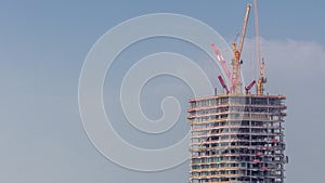 Tower cranes working on the construction site of new skyscraper high-rise building aerial timelapse. Dubai