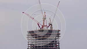 Tower cranes working on the construction site of new skyscraper high-rise building aerial timelapse. Dubai