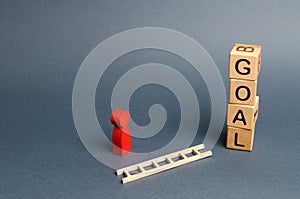 tower of cubes with an inscription goal and a red figure of a man stands near fallen ladder. concept of achieving the goal