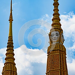 Tower with extraordinary white faces of Buddha in residence of the King of Cambodia. Golden spire topping the golden roof.