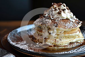 A tower of fluffy pancakes piled high, smothered in creamy whipped cream, and sprinkled with indulgent chocolate chips