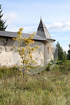 The tower of the fortress wall in the grass, Pskov-Pechory Dormition Monastery in Pechory, Pskov region, Russia under blue sky