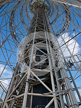 A tower with a high-speed elevator against a blue sky with clouds