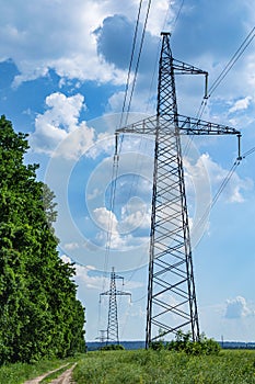 Tower with high-voltage energy transmission wires against the blue sky.