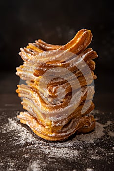 A tower made of churros with a black backdrop. Churros are a type of fried dough pastry, often covered in sugar and can be enjoyed